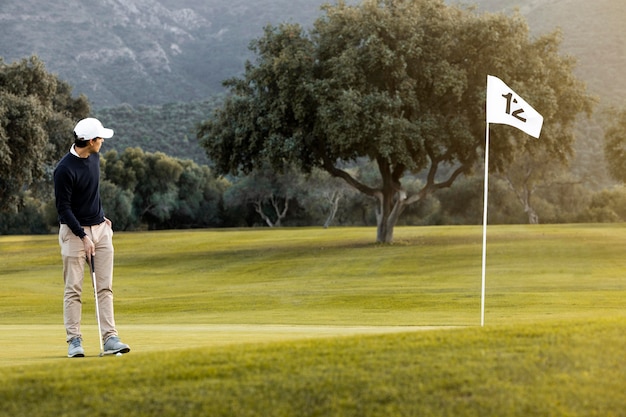 Человек на поле для гольфа рядом с флагом