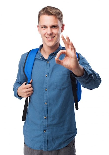 Man grabbing the grips of a blue backpack and saying ok