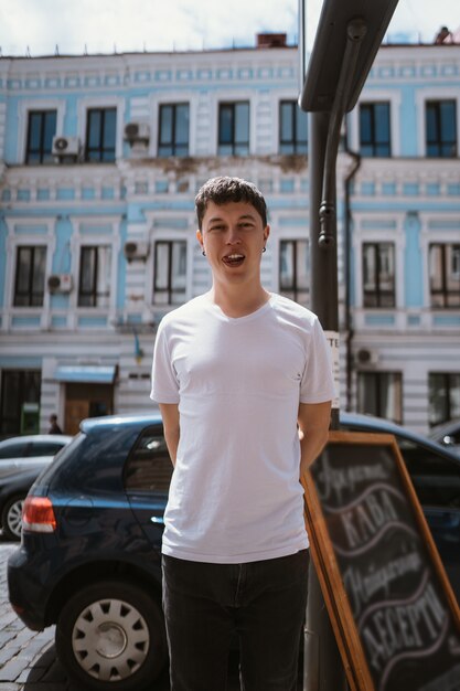 灰色のtシャツとジーンズの街の通りの背景の上の男