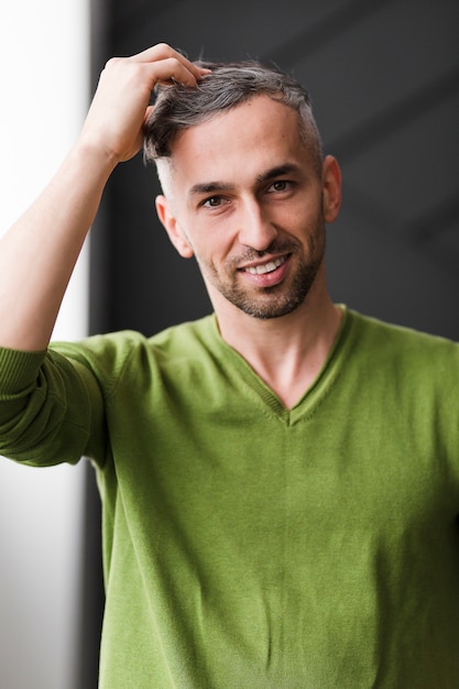 Foto gratuita uomo in camicia verde che organizza i suoi capelli