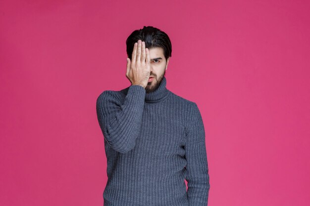 Man in grey sweater looking across his fingers