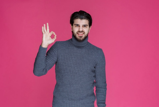 Man in grey sweater making positive and good hand sign.