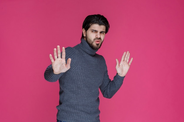 Man in grey sweater trying to stop or preventing something