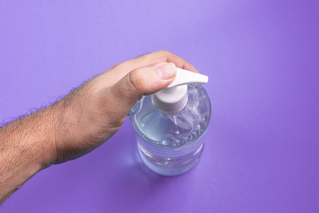 Man hand in container with alcohol gel on the light blue