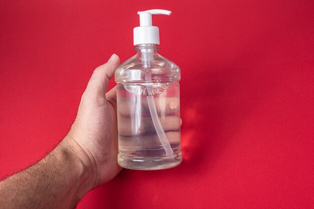 Man hand in container with alcohol gel on the red