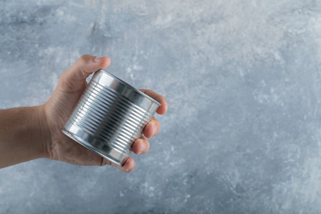 Man hand holding a metallic can on marble.