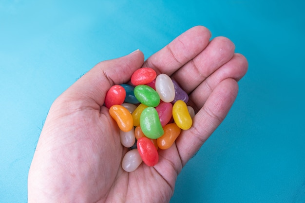 Man hand holding various jelly beans on the blue background