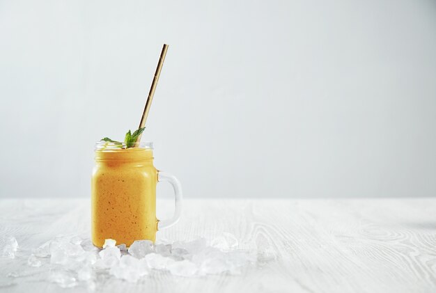 Man hand takes transparent rustic jar with tasty healthly freshly made yellow smoothie from mango