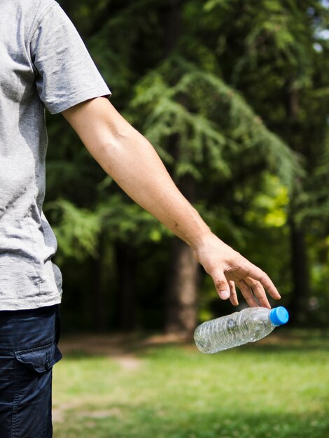 Man hand throwing plastic water bottle in park