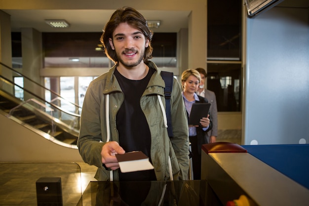 Foto gratuita uomo che consegna la sua carta d'imbarco al bancone