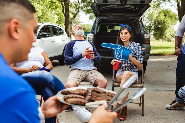 Free photo man handing out burgers at a tailgate party