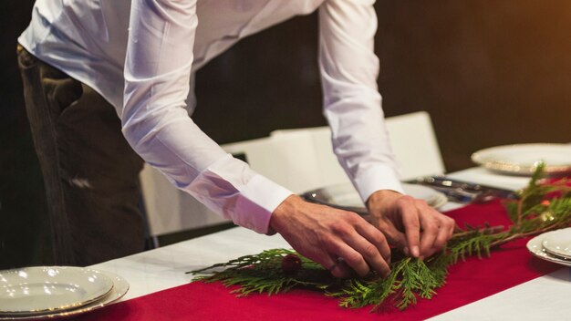 Man hands decorating table with fir tree branch