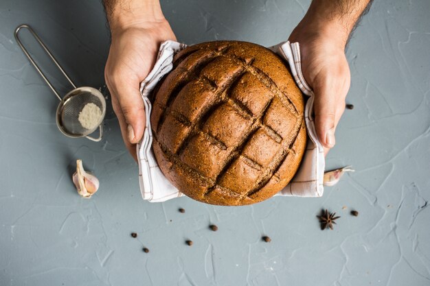 Man hands holding rye bread in towel