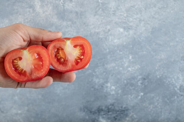 赤いトマトのスライスを持っている男の手。高品質の写真