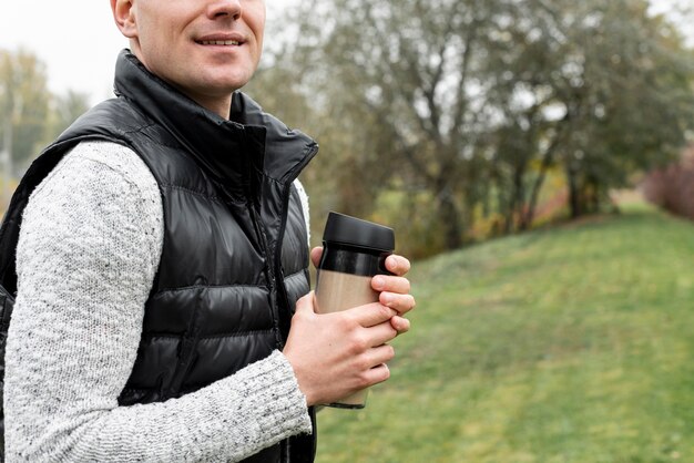 Free photo man hands holding a thermos in nature