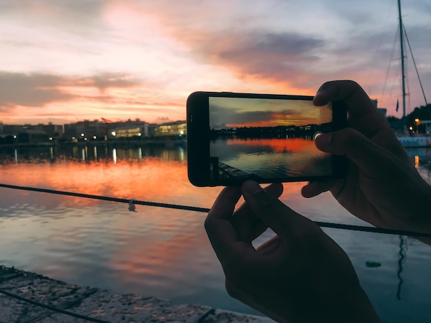 夕日の携帯電話で写真を撮る男の手