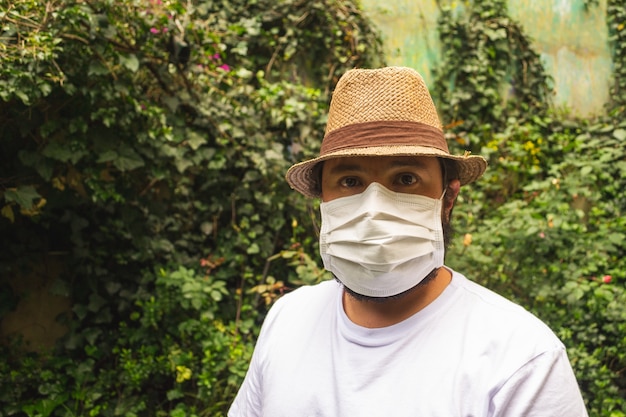 Uomo con cappello e camicia bianca che indossa una maschera per proteggersi dalla polvere e dal coronavirus