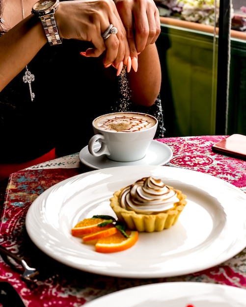 Free photo man having coffee with desert tartlets with cream and orange side view
