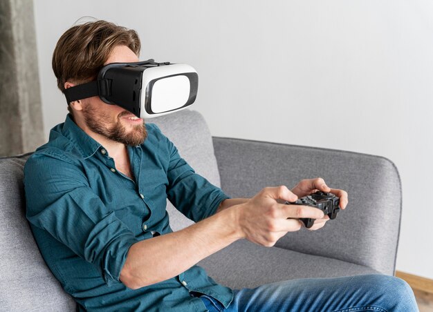 Man having fun at home on the couch with virtual reality headset playing video games