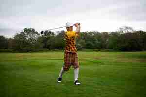 Free photo man having a game of golf outdoors on the field