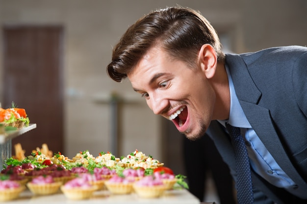 Foto gratuita l'uomo che ha grande desiderio di mangiare tartellette a buffet