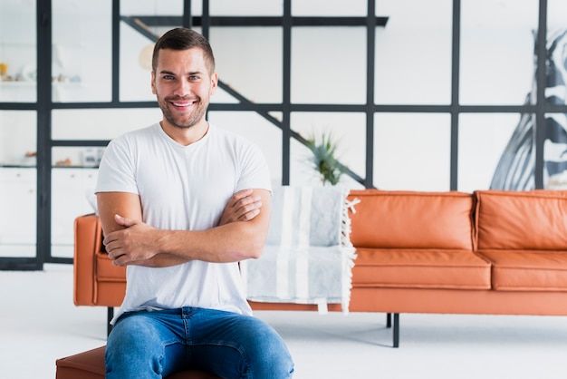 Man having his arm crossed and sitting on a stool