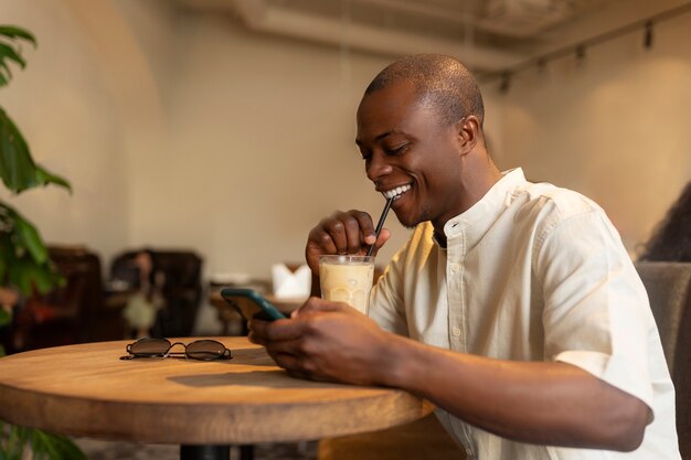 スマートフォンを使用しながらアイスコーヒーの休憩をとっている男