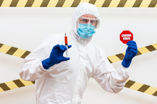 man in hazmat suit with coronavirus stop sign