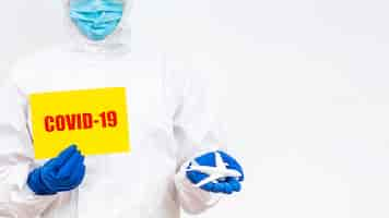 Free photo man in hazmat suit with covid-19 sign