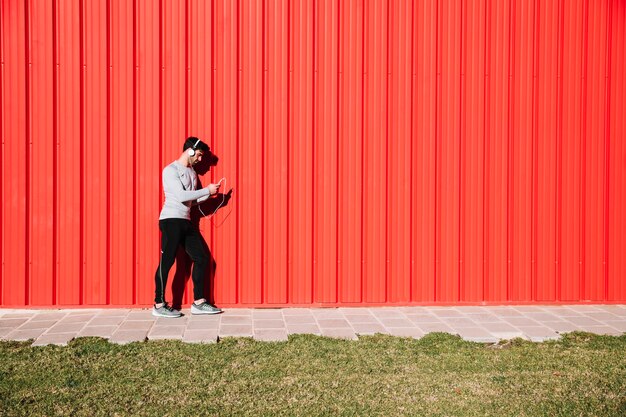 Man in headphones resting near red wall