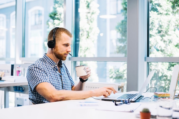 Free photo man in headset drinking and working