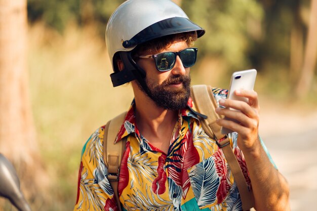 Man in helmet sitting on motorbike and using mobile phone