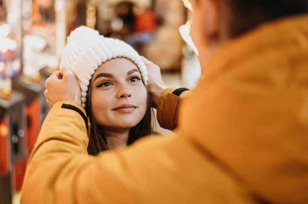 Man helping his girlfriend to put a beanie on