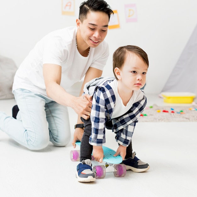 Man helping toddler using skateboard