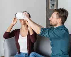 Free photo man helping woman put on virtual reality headset