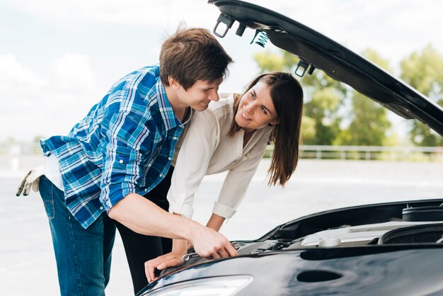 男は女性が彼女の車を修正するのに役立ちます