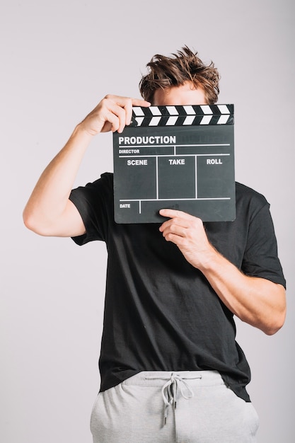 Man hiding his face behind clapperboard