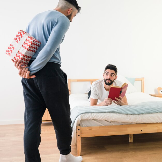 Man hiding present form his boyfriend reading the book