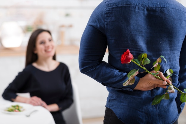 Foto gratuita uomo che nasconde una rosa dalla sua ragazza