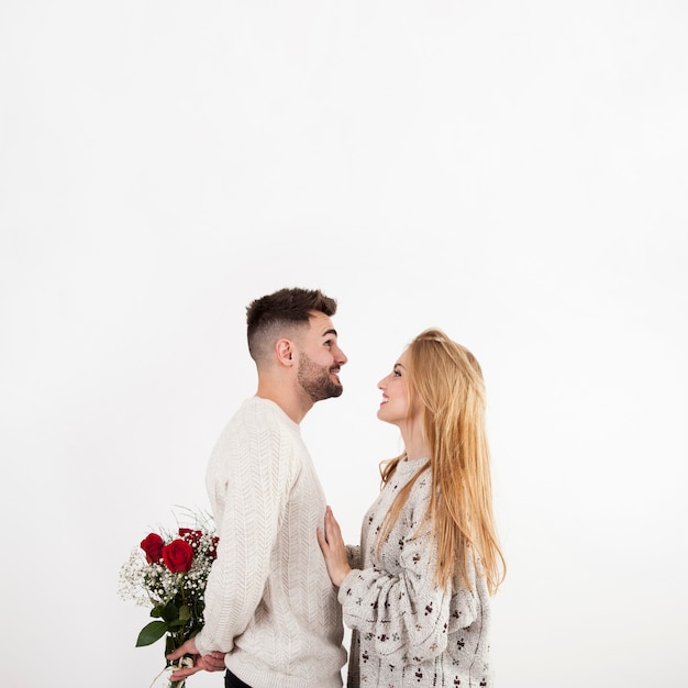 Man hiding roses from woman