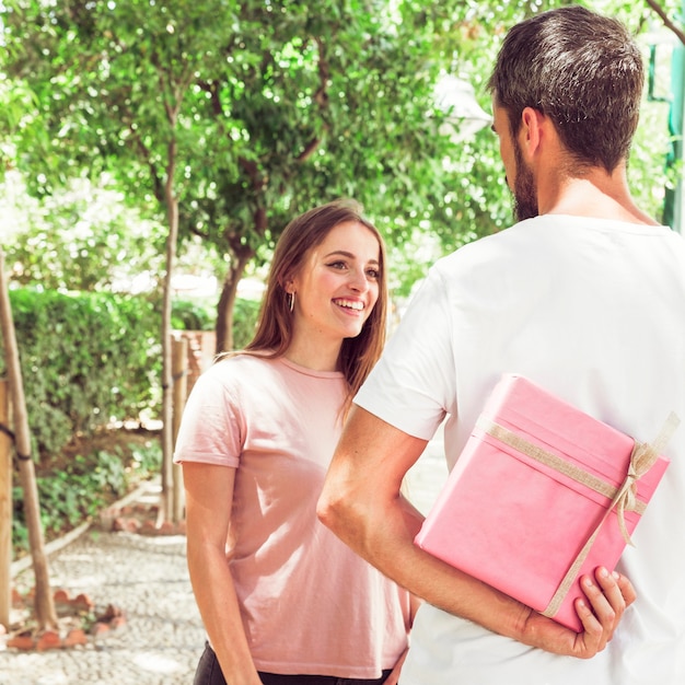 Foto gratuita uomo che nasconde il regalo di san valentino dalla sua ragazza felice