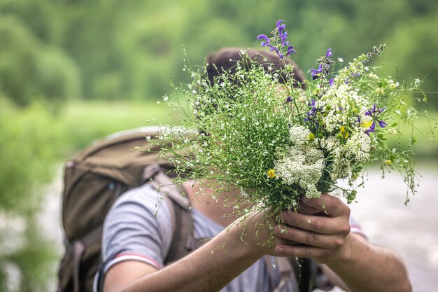 하이킹을 하는 남자가 야생화 꽃다발을 들고 있다
