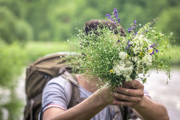 A man on a hike holds a bouquet of wildflowers