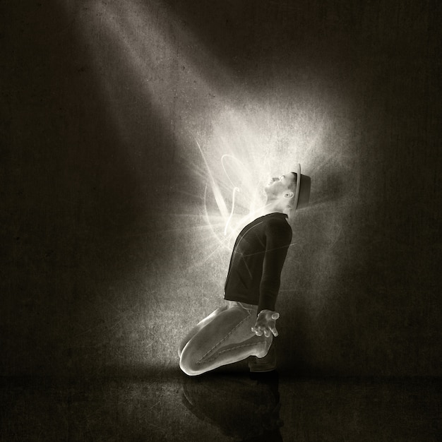 Man on his knees with a ray of light 