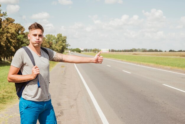 男は道路でヒッチハイク