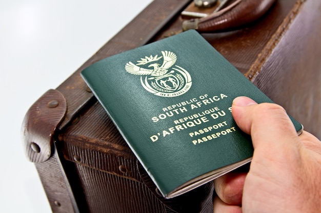 Free photo man holding an african passport on a brown luggage