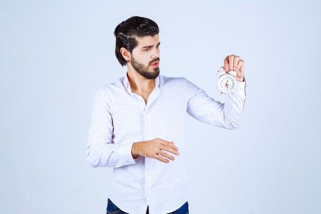 Man holding an alarm clock and confused as he is late