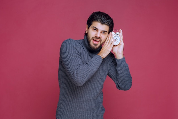 Man holding an alarm clock and sleeping. 