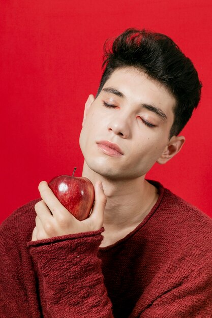 Man holding apple with closed eyes