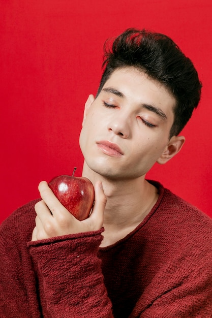 Мужчина держит яблоко с закрытыми глазами